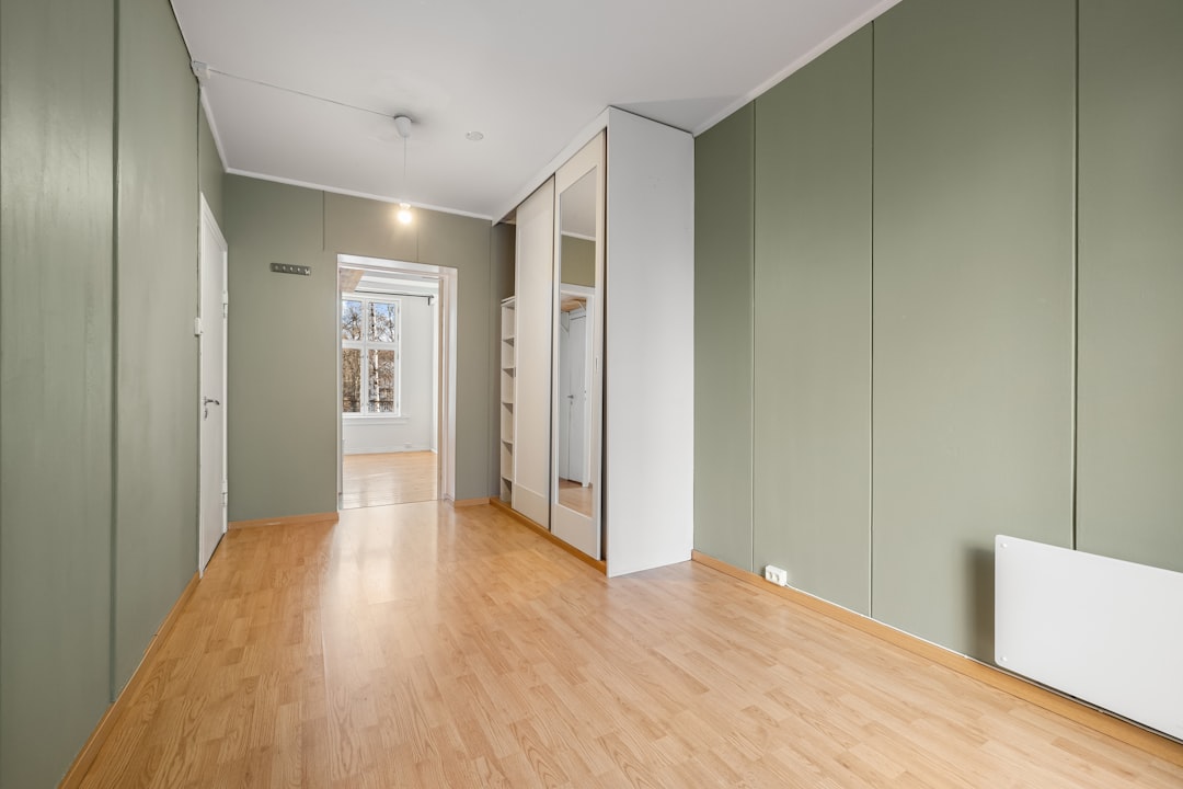 a-room-with-a-hard-wood-floor-and-green-walls-el-0fs4pyfg