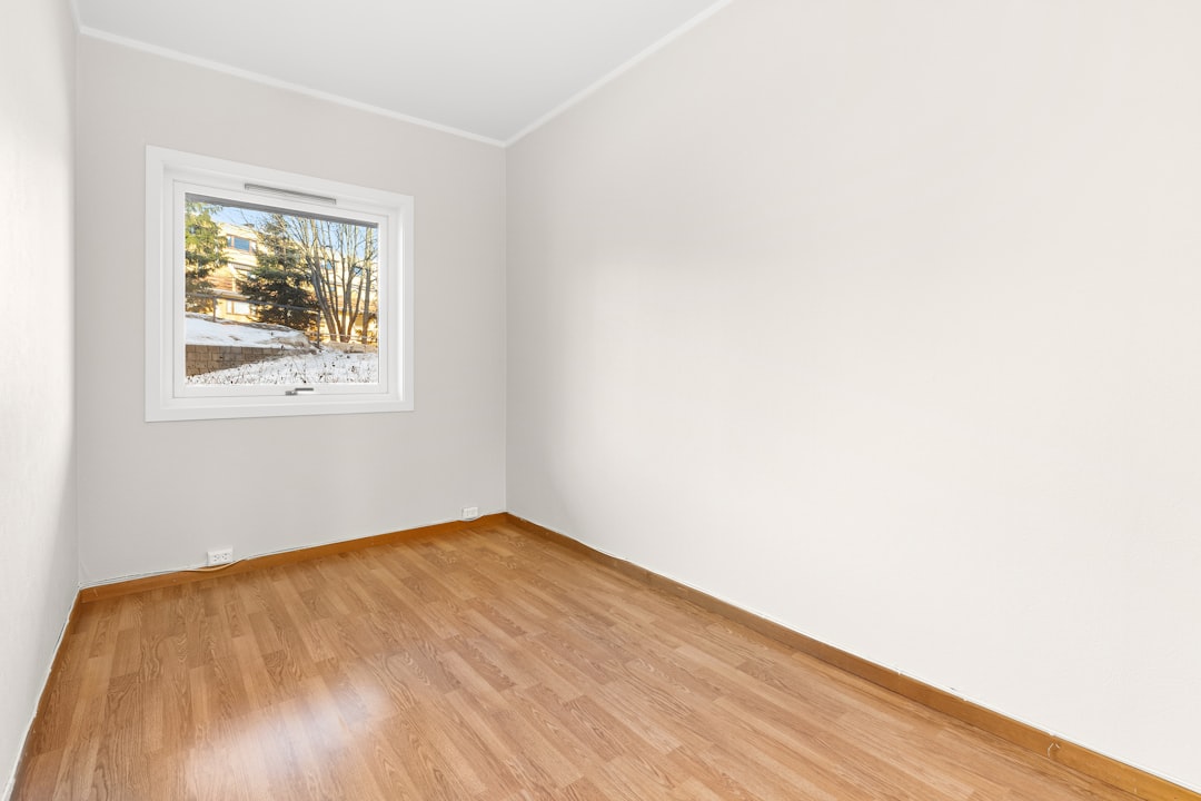 an-empty-room-with-hard-wood-floors-and-a-window-qtpq7tlyodc