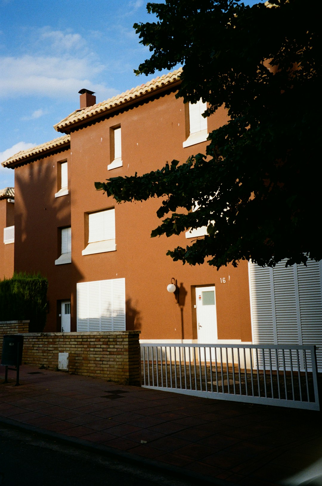 brown-building-with-white-shutters-and-doors-udcubfv0aa4