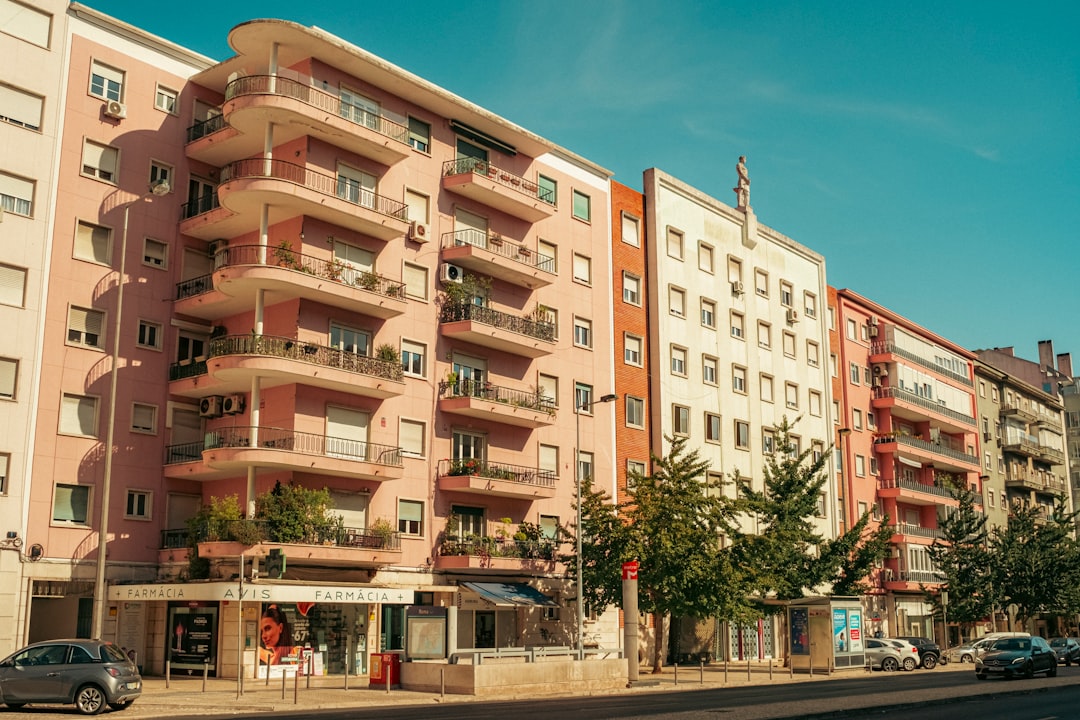 A pink apartment building at Avenida de Roma, 56 in Lisbon, Portugal. Near an exit from Roma metro station. Photo made in Summer 2025. Shot with Fujifilm XM5 and Viltrox 25/1.7